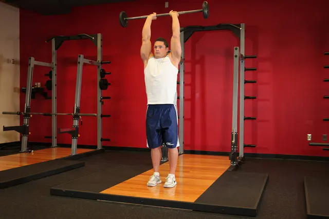 Standing Overhead Barbell Triceps Extension, finishing position